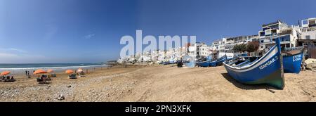 Morocco, Africa: panoramic view of old boats and the skyline on the beach of Taghazout, small berber fishing village near Agadir Stock Photo