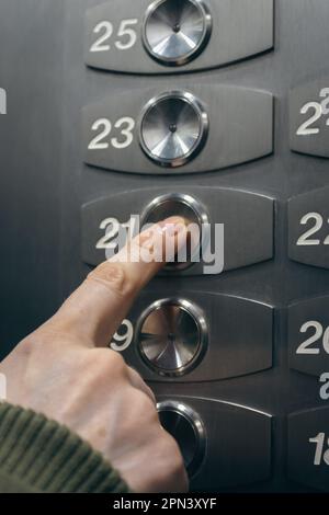 Finger on lift button. Woman touching elevator button. Choice of level in elevator. Panel of floor numbers. Modern elevator interior. Stock Photo