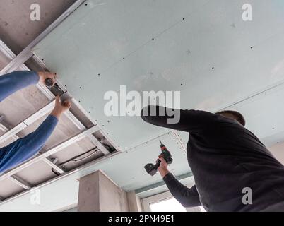 Man assembles profile metal frame for plasterboard ceilings Stock Photo