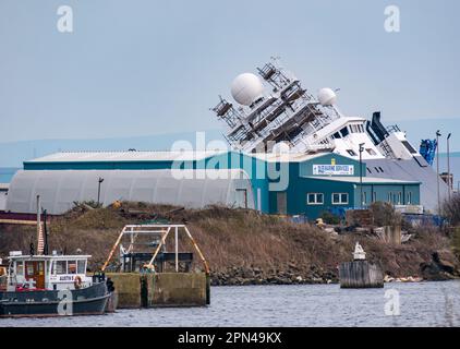 Ship Petrel lying on its side in dry dock after tipping over in an accident, Leith Harbour, Edinburgh, Scotland, UK Stock Photo