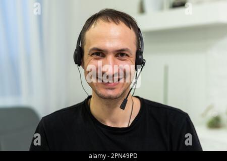 Smiling young man working on laptop in modern kitchen, checking email in morning, writing message in social network, happy young male using internet Stock Photo