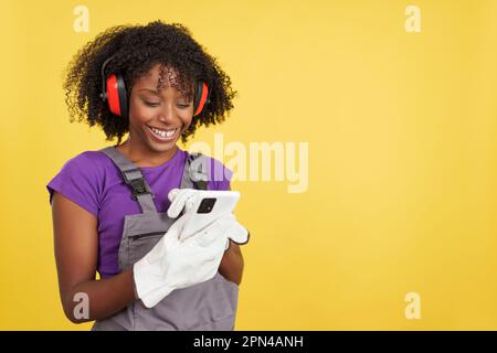 Afro female carpenter standing using the mobile Stock Photo