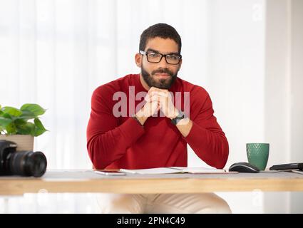 Happy handsome man wearing eyeglasses photographer posing at workplace Stock Photo