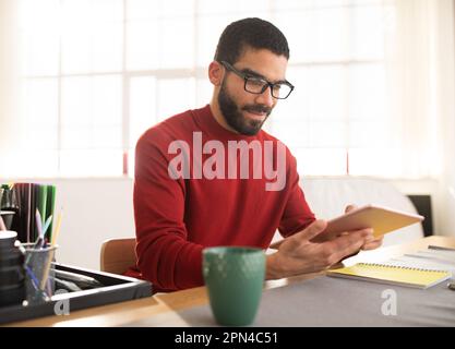 handsome hispanic man wearing eyeglasses using digital tablet at office Stock Photo