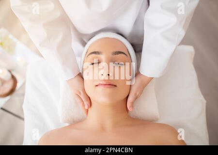 Young indian woman enjoying face lifting massage, top view Stock Photo