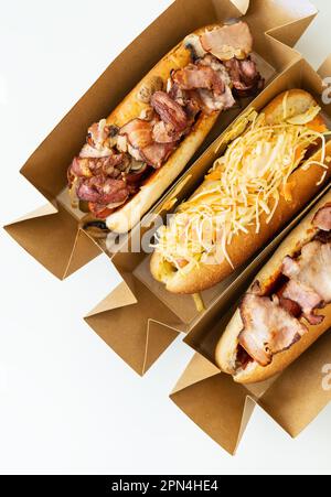 Delicious hot dog grilled in a restaurant, homemade hot dogs wrapped in bacon, with onions and mushrooms, salad. Street food, delivery, takeout Stock Photo