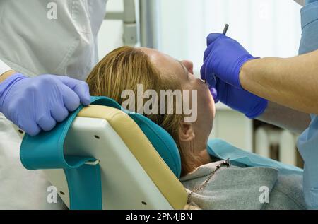 The dentist treats the teeth of the patient in the clinic. Close-up of the face, gloved hands, tools for dental treatment. Stock Photo