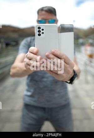 Mature man, white holding cell phone to take photos, background bokeh blur Stock Photo