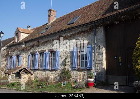 Flagy, France, has 7 public wells built by command of Louis VII. This one decorates a garden in front of a blue-shuttered, single-storey stone house. Stock Photo