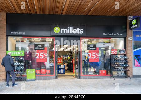 Man browsing in front of Millets shop, business selling outdoor clothing, Bracknell town centre, Berkshire, England, UK Stock Photo