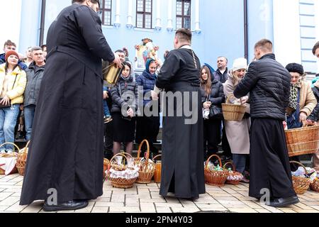 A priest blesses Easter food with Holy Water as Ukrainian believers attend the Easter Sunday traditional celebration at St. Michael's Golden-Domed Monastery in central Kyiv. According to the tradition the faithful bring their Easter food in a basket to be purified, it is always Pasha (Easter bread), painted egg (pysanka) among other. Most of Ukrainians are Orthodox Christians or Greek Catholic Christians, both observe the eastern rite of Easter. Kyiv remains relatively peaceful as the Russian invasion continuous and Ukraine prepares for a spring counter-offensive to retake Ukrainian land occup Stock Photo
