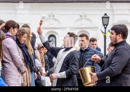 A priest blesses Ukrainian believers with Holy Water as they attend the Easter Sunday traditional celebration in St. Michael's Golden-Domed Monastery in central Kyiv. According to the tradition the faithful bring their Easter food in a basket to be purified, it is always Pasha (Easter bread), painted egg (pysanka) among other. Most of Ukrainians are Orthodox Christians or Greek Catholic Christians, both observe the eastern rite of Easter. Kyiv remains relatively peaceful as the Russian invasion continuous and Ukraine prepares for a spring counter-offensive to retake Ukrainian land occupied by Stock Photo