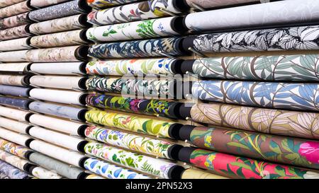 Samples of different wallpapers on store window racks, Various textures and colors of paper for wall. Stock Photo