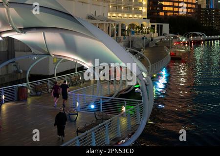 People enjoying time walking on pedestrian riverwalk trail alongside river water in downtown district of Tampa city in Florida, USA. Recreational area Stock Photo