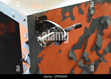 An old pencil sharpener mounted to a cabinet with pealing paint in a school abandoned since 2001. Stock Photo