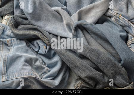 Lots of crumpled jeans pants, close up. Denim background. The concept of buying, selling, shopping and trendy modern clothes Stock Photo