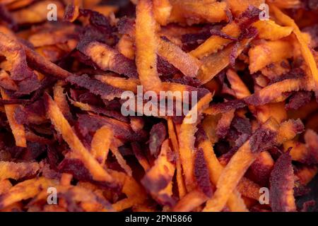 Sliced into thin slices of red-orange carrots in the kitchen, several cleaned of dirt and washed carrots grated into pieces on a grater Stock Photo