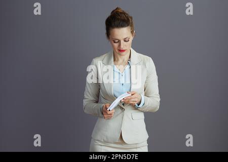 pensive modern business woman in a light business suit with euros money packs against grey background. Stock Photo