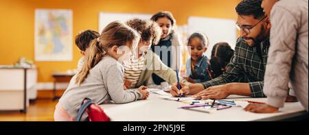 An art teacher showing her students how to draw on easels in art class ...