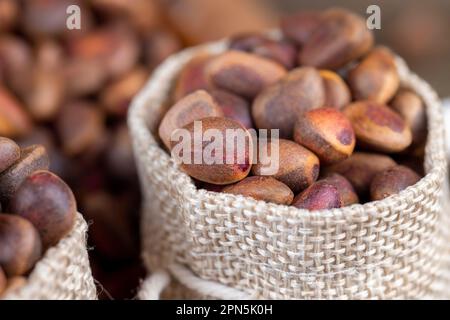 Unpeeled pine nuts on the table, a bunch of pine nuts in the shell Stock Photo