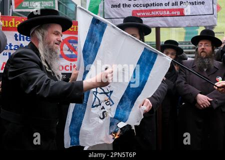 London, UK. 16th April, 2023. Orthodox jews, from the Naturei Kata group, supportive of Palestinian self-determination set an Israeli flag alight. The Al-Quds march took place between the home Office and Whitehall, held close to final Friday of Ramadan annually. The event was begun to oppose discriminatory Israeli policies, Zionism and show solidarity with the people of Palestine. A small Israeli counter-protest was kept separated from the march by police officers. Credit: Eleventh Hour Photography/Alamy Live News Stock Photo