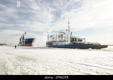 April, 2023 - Arkhangelsk. Dry cargo ship 'Bering' and icebreaker 'Captain Chaadaev'. Icebreaking operations on the Northern Dvina River. Russia, Arkh Stock Photo