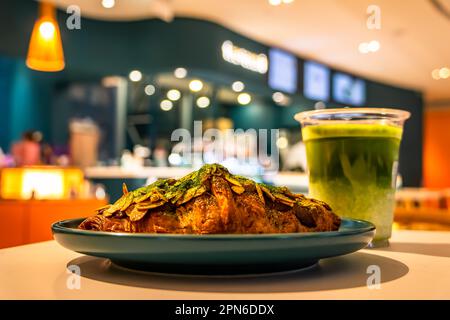 Flaky croissant filled with green tea and almond paste. Topped with flaked almonds and matcha powder. Stock Photo