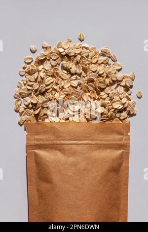 Brown kraft paper pouch bags with oats top view with harsh shadow on white background. Oatmeal cereal porridge pack flat lay. Rolled oat flakes packag Stock Photo
