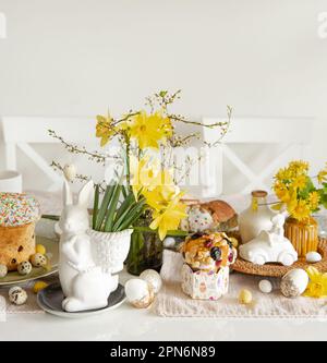Easter holiday table with eggs, traditional pastries and flowers daffodils. Stock Photo