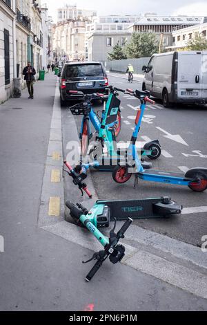 Rental E-scooters from various companies parked and fallen in a designated parking area on a street in Paris, France. Stock Photo