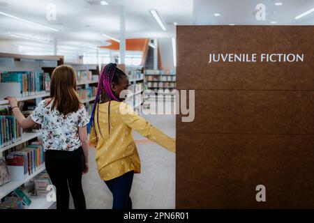 Two elementary aged girls exploring public library Stock Photo
