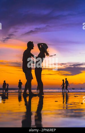 Young couple having fun on the ocean beach. Sunset in Bali. Stock Photo