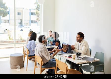 Multiracial colleagues discussing while sitting in coffee shop Stock Photo