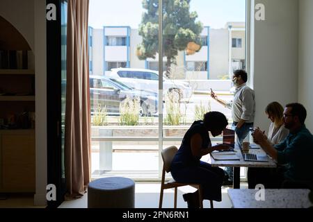 businessman talking on video call standing near window in cafe Stock Photo