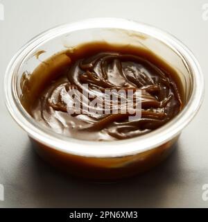 Salted Caramel sauce in glass bowl on white marble background. Butter, sugar with cream and salt.  Stock Photo