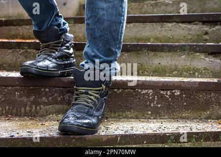 A man in boots on the old steps, close-up. Stock Photo