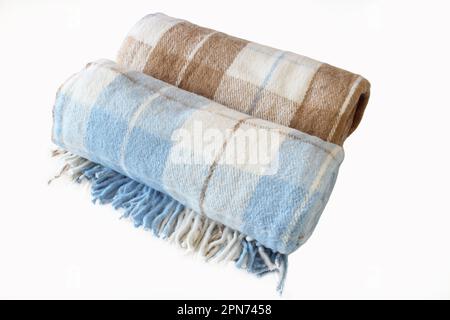 Woolen checkered plaid blanket isolated on a white background. Beige-brown and white-blue rolled blanket. Close up. Stock Photo