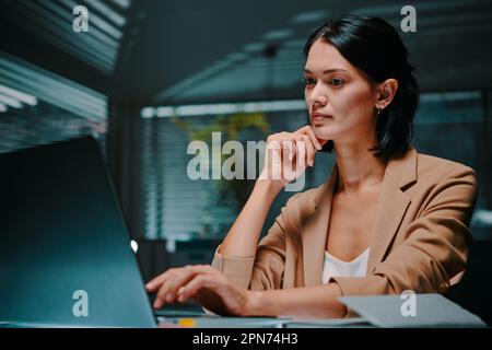 Portrait of serious pensive young businesswoman reading data on laptop screen Stock Photo