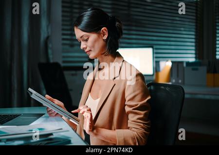 Young female entrepreneur reading report on digital tablet Stock Photo