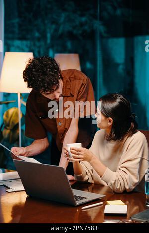 Business colleagues discussing details in report when working late at night Stock Photo