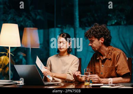 Marketing team discussing chart at late night meeting Stock Photo