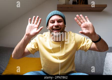 Man smiling and waving hands during online meeting. Stock Photo