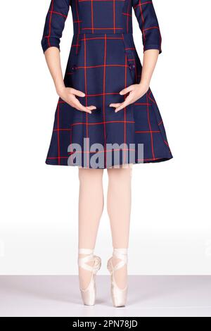 En Pointe INCORRECT heels NOT together hands bras bas teachers perspective Young female ballet dancer on white background tartan dress pink silk and s Stock Photo