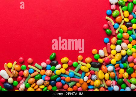 Mixed collection of colorful candy, on colored background. Flat lay, top view. frame of colorful chocolate coated candy. Stock Photo