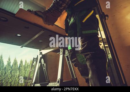 Bottom View of Professional Carpenter Cutting Wooden Plank in His Workshop Using Manual Power Woodworking Saw. Stock Photo