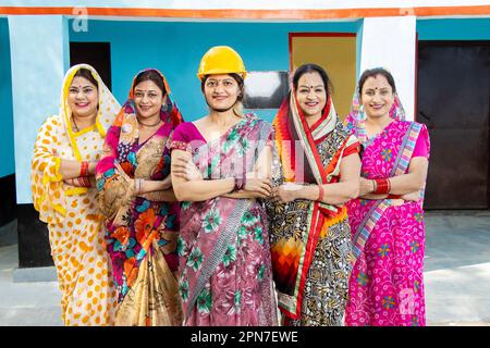 Group of confident young indian women wearing sari standing with female engineer wearing yellow hard hat standing cross arms. concept of woman empower Stock Photo