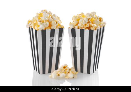 Two black white striped carton buckets with tasty cheese popcorn, isolated on white background. Box with scattering of popcorn grains. Movies, cinema Stock Photo