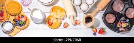 Summer baking background with baked pastry - berry cakes, muffins, mini pie tarts, with cooking baking ingredients, flour, eggs, rolling pin, cream mi Stock Photo