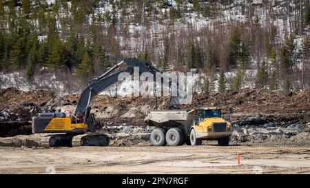 Dumper being filled by an excavator during excavation work in the forest in winter Stock Photo