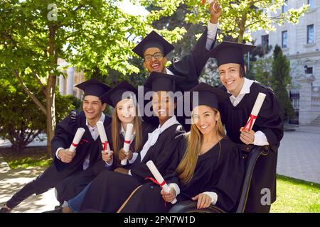 Laughing excited group of multicultural people in graduation gowns and caps graduate universuty. Stock Photo